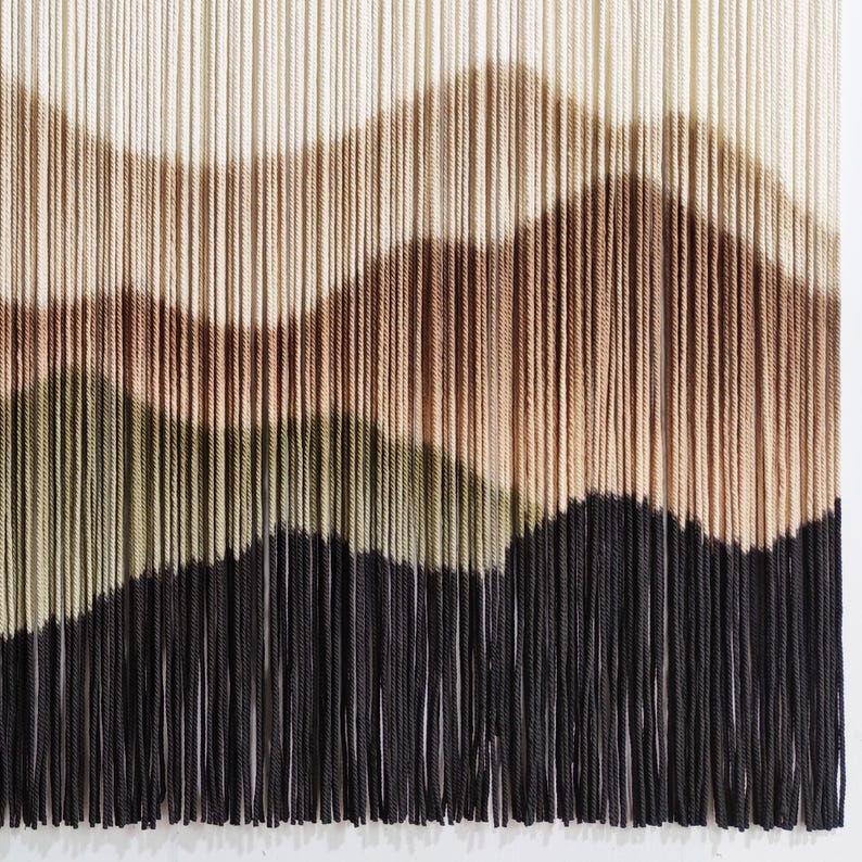 May include: A wall hanging made of yarn with a wavy pattern in shades of brown, green, and black.