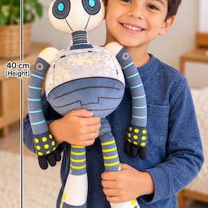 May include: A plush robot toy with a round white head, blue circular eyes, and a grey torso featuring a mottled pattern. The arms and legs have blue and yellow striped accents, with black hands and feet. It measures 40 cm in height and 20 cm in width.