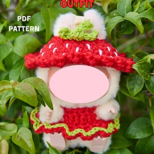 May include: A plush doll wearing a red and white strawberry outfit, with a green crocheted stem. The text "MONSTER DOLL STRAWBERRY OUTFIT" is at the top, with "PDF PATTERN" and "DIGITAL DOWNLOAD" on the sides.