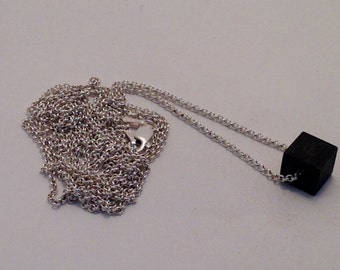 May include: A silver chain necklace with a black cube pendant.
