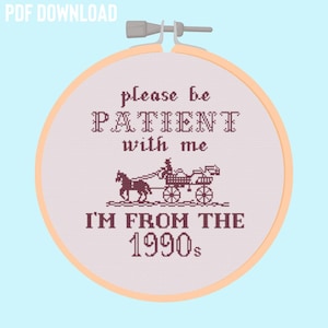 Op de afbeelding: Een roze en witte borduurring met de tekst "please be PATIENT with me I'M FROM THE 1990s" en een klein beeld van een koets met paarden.