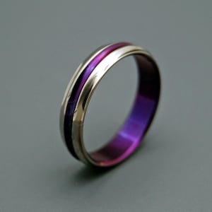 May include: A silver titanium ring with a purple and pink inlay.