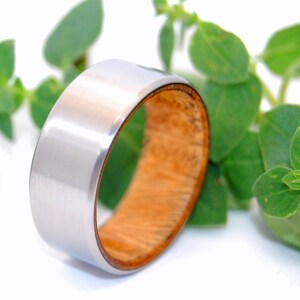 May include: A silver and wood ring with a brushed silver finish. The ring is made of titanium and wood.