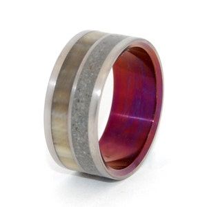 May include: A titanium ring with a band of concrete and a white inlay. The inside of the ring is a deep purple color.