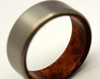 May include: A silver titanium ring with a brown wood inlay. The ring is smooth and polished.