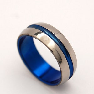 May include: A titanium ring with a blue inlay. The ring is polished and has a smooth finish.