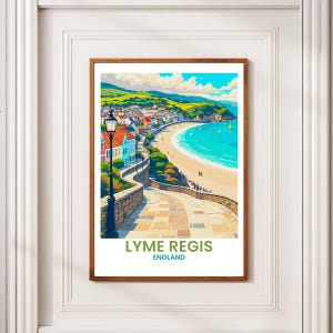 May include: A framed print of Lyme Regis, England, featuring a coastal town with colorful buildings, a sandy beach, and turquoise water. The artwork includes a winding stone path and the text "LYME REGIS ENGLAND".