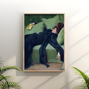 May include: A framed art print of a woman reclining on a green sofa, holding a book. The woman is dressed in a long black dress. The artwork has a vintage aesthetic, with a wooden frame and a signature in the bottom right corner.