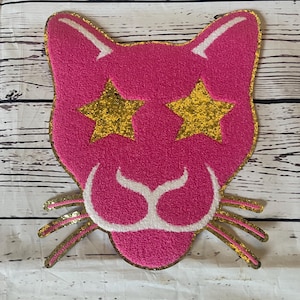 May include: Pink cat face with gold glitter stars for eyes and gold glitter whiskers.