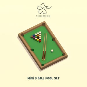 May include: A miniature pool table set featuring a green felt surface with brown rails, six pockets, a triangular rack of colorful billiard balls, two cues with red accents, and a white cue ball. The text MIODA STUDIO and MINI 8 BALL POOL SET appear.