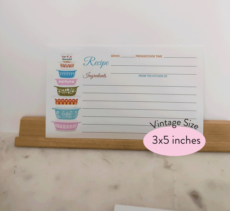 May include: A white recipe card with a stack of colorful vintage mixing bowls. The card has lines for writing down a recipe, including the title, ingredients, servings, preheat/cook time, and from the kitchen of. The card is 3x5 inches.