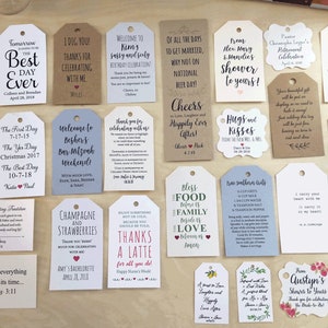 May include: A collection of various gift tags with handwritten text in black ink. The tags are in different shapes and sizes, with messages for weddings, birthdays, and other celebrations. Some tags have decorative elements like hearts and floral designs.