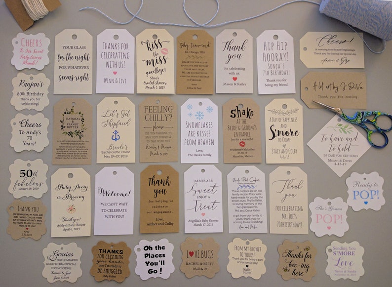 May include: Assortment of decorative tags with various messages for celebrations, including birthdays, weddings, and baby showers. The tags are in different shapes and sizes, with a variety of fonts and colors. A pair of scissors and twine are also present.