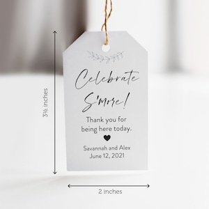 May include: A white tag with black text that reads "Celebrate S'more!"  Thank you for being here today. Savannah and Alex June 12, 2021. The tag is 3 1/2 inches tall and 2 inches wide.