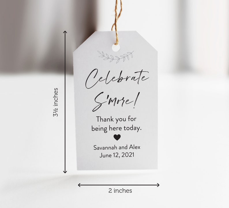 May include: A white tag with black text that reads "Celebrate S'more!"  Thank you for being here today. Savannah and Alex June 12, 2021. The tag is 3 1/2 inches tall and 2 inches wide.
