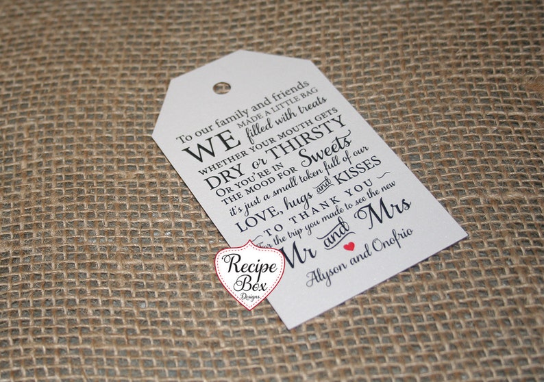 May include: White wedding favor tag with black text that reads "To our family and friends WE made a little bag filled with treats WHETHER YOUR MOUTH GETS DRY or THIRSTY OR YOU'RE IN THE MOOD FOR Sweets it's just a small token full of our LOVE, hugs and KISSES TO THANK YOU~ for the trip you made to see the new Mr and Mrs Alyson and Onofrio".