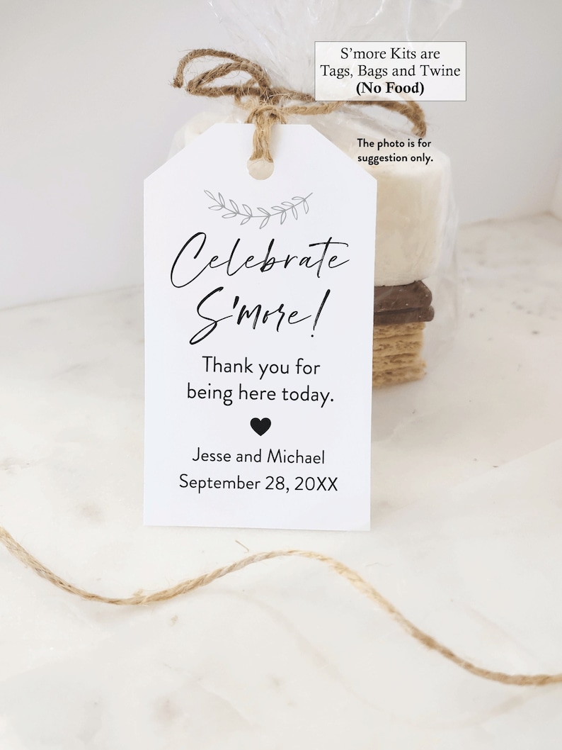 May include: White tag with black text that reads "Celebrate S'more!"  Thank you for being here today. Jesse and Michael September 28, 20XX. The tag is tied with twine to a brown paper bag with a white marshmallow inside.