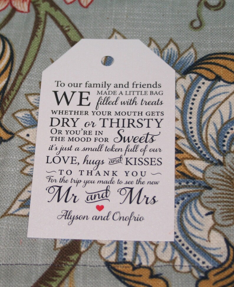 May include: White favor tag with black text that reads "To our family and friends, we made a little bag filled with treats, whether your mouth gets dry or thirsty or you're in the mood for sweets, it's just a small token full of our love, hugs and kisses, to thank you for the trip you made to see the new Mr and Mrs Alyson and Onofrio."
