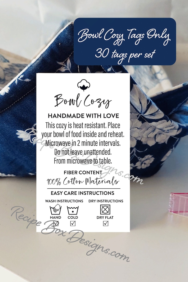 May include: A white tag with black text that reads "Bowl Cozy Handmade with Love". The tag also includes instructions for using and caring for the cozy, including washing and drying instructions. The tag is on a blue and white floral fabric background.
