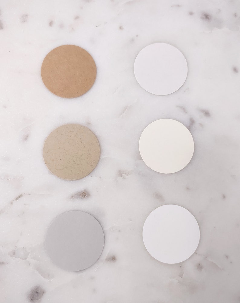 May include: Six round paper samples in different shades of white, beige, and brown. The samples are arranged in two vertical rows of three.