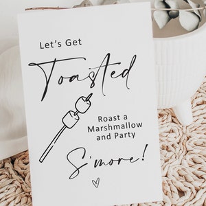 May include: White card with black text that reads "Let's Get Toasted" with a drawing of a marshmallow on a stick. The text below the drawing reads "Roast a Marshmallow and Party S'more!" with a small heart symbol.