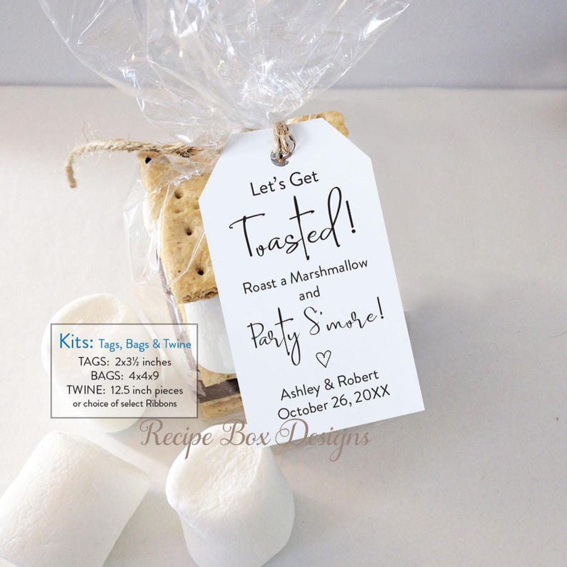 May include: A clear cellophane bag tied with twine, containing a graham cracker and marshmallow s'more. A white tag with the text "Let's Get Toasted!" is attached. The tag also includes the names Ashley & Robert and the date October 26, 20XX.
