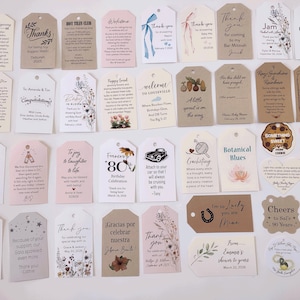 May include: A collection of assorted gift tags and labels in various shapes and sizes. The tags feature printed text, floral designs, and decorative elements. Some tags include phrases like "Thank You," "Happy Birthday," and "Welcome."