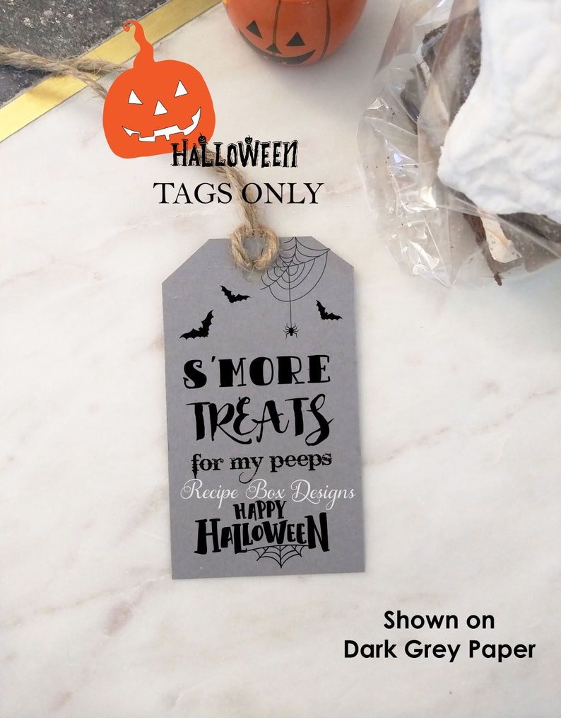 May include: A gray Halloween gift tag with the text "S'MORE TREATS for my peeps HAPPY HALLOWEEN". The tag has a spider web and bat design. The image also includes a pumpkin decoration and the text "HALLOWEEN TAGS ONLY".