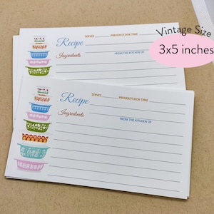 May include: Two white recipe cards with blue and brown text. The cards feature a stack of colorful vintage-style kitchen bowls. The cards are 3x5 inches.
