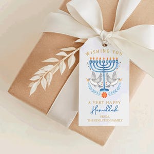 May include: A gift box wrapped in brown paper with a white ribbon and a decorative tag. The tag features a blue menorah, doves, and the text "Wishing You A Very Happy Hanukkah".