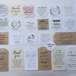 May include: A collection of various thank you tags and labels with different shapes and sizes. The tags feature printed text in various fonts and colors, with some including floral or decorative elements. The tags are for weddings, baby showers, and other special events.