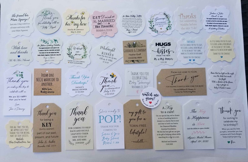 May include: A collection of various thank you tags and labels with different shapes and sizes. The tags feature printed text in various fonts and colors, with some including floral or decorative elements. The tags are for weddings, baby showers, and other special events.