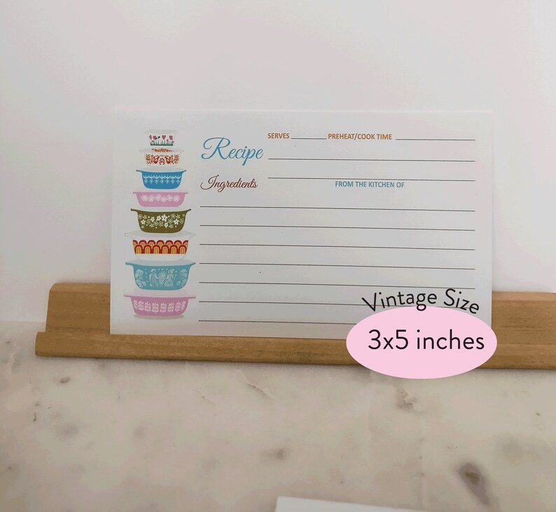 May include: A white recipe card with a stack of colorful vintage mixing bowls. The card has lines for writing down a recipe, including the title, ingredients, servings, preheat/cook time, and from the kitchen of. The card is 3x5 inches.