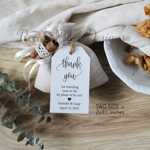 May include: A white thank you tag with black text that reads "thank you for traveling near or far by plane or by car! Jennifer & Gage April 15, 2023". The tag is attached to a small burlap bag with cinnamon sticks inside. The tag size is 2x3 1/2 inches.