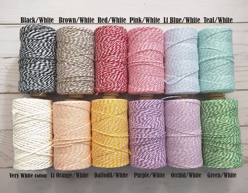 May include: A collection of twine spools in various colors, including black/white, brown/white, red/white, pink/white, light blue/white, and teal/white. Additional colors are very white cotton, light orange/white, daffodil/white, purple/white, orchid/white, and green/white. Each spool is labeled with its color combination.
