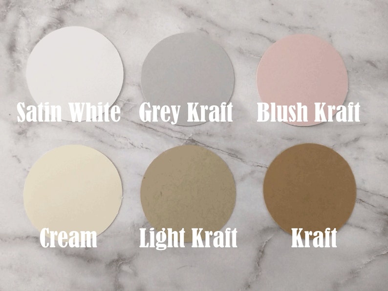 Puede incluir: Seis muestras de papel redondas en diferentes colores y texturas. Los colores son blanco satinado, kraft gris, kraft rubor, crema, kraft claro y kraft.