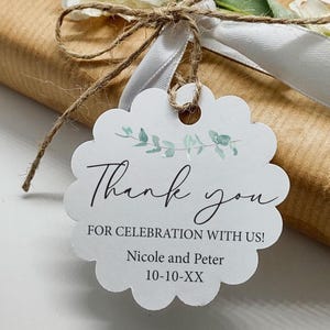 May include: A gift wrapped in brown paper, tied with twine and a white ribbon. A white scalloped tag with the words "Thank you" and "For Celebration With Us!" is attached. The tag includes names and a date.