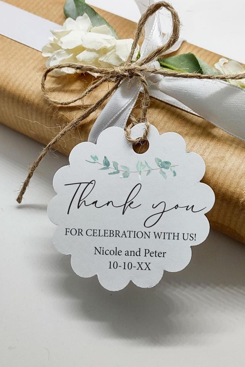 May include: A gift wrapped in brown paper, tied with twine and a white ribbon. A white scalloped tag with the words "Thank you" and "For Celebration With Us!" is attached. The tag includes names and a date.