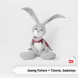 May include: A grey plush bunny with long ears and a red and white plaid scarf. The bunny is sitting with its legs extended. The text "Sewing Pattern + Tutorial, Sankatoys" is at the bottom of the image.