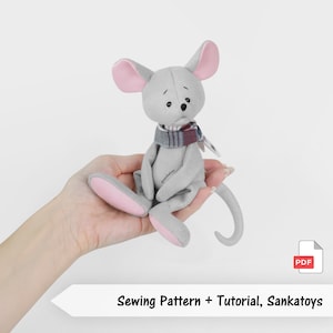 May include: A gray plush mouse toy with pink ears and feet, wearing a scarf with red and blue stripes. The mouse is sitting and has a sad expression. The image includes the text "Sewing Pattern + Tutorial, Sankatoys".