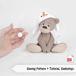 Puede incluir: Un oso de peluche marrón con un gorro blanco con nariz de zanahoria y ojos negros. El oso está sentado con las piernas extendidas. La imagen incluye el texto "Sewing Pattern + Tutorial, Sankatoys".