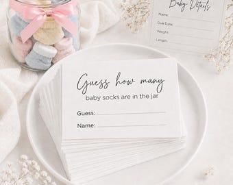 May include: A glass jar filled with small pastel baby socks tied with a pink ribbon, accompanied by a stack of white game cards reading Guess how many baby socks are in the jar, and a white card labeled Baby Details with lines for information.