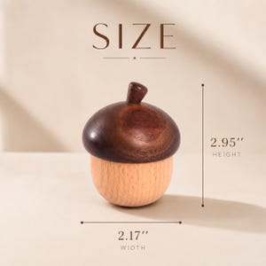 May include: A wooden acorn-shaped container with a dark brown cap and a light tan base. The text SIZE is at the top. A vertical line indicates a height of 2.95 inches, and a horizontal line indicates a width of 2.17 inches for the object.