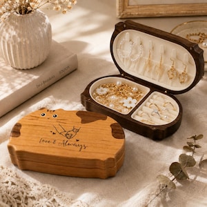 May include: A wooden jewelry box shaped like a cat with a dark brown finish. The lid features a graphic of two hands holding each other and the text "Love & Always". The open box reveals a cream-colored interior with hooks for earrings and compartments for rings and necklaces.