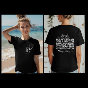 以下が含まれることがあります： 前面に白いハートと「Let Them」という文字が書かれた黒いTシャツ。後ろには「Let Them Misunderstand You, Judge You, Gossip and Doubt You, Your Worth Has Already Been Affirmed By God. Keep Shining.」という文字が書かれています。