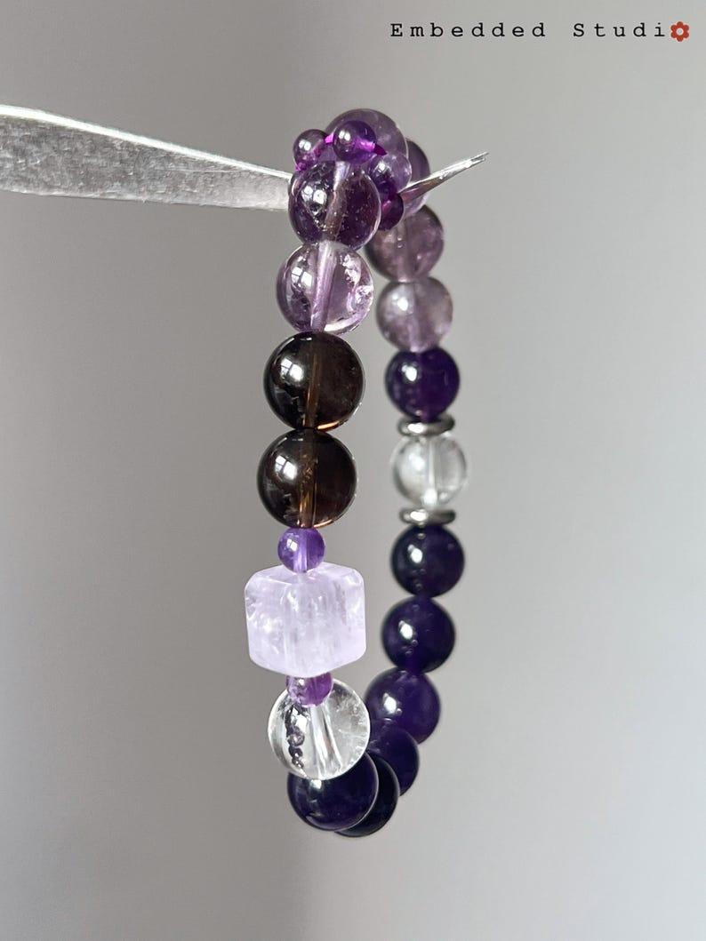 Hand holding the amethyst bracelet to showcase bead clarity and size.
