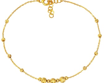 May include: A gold anklet with a delicate chain and small round beads. The beads are clustered together in the center of the anklet.