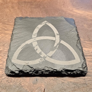 May include: A black slate coaster with a white Celtic knot design. The knot is a symbol of unity, strength, and eternity.