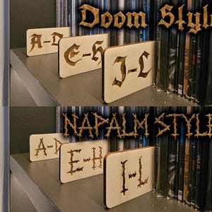 Puede incluir: Dos filas de separadores de madera con etiquetas para una estantería. La fila superior está etiquetada como "Doom Style" con las letras A-D, E-H y J-L. La fila inferior está etiquetada como "NAPALM STYLE" con las letras A-D, E-H e I-L.