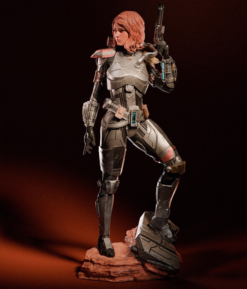 May include: A detailed figurine of a woman in futuristic armor, holding a gun. The figure is predominantly silver and black, with red accents on the shoulders and knee. The woman has red hair and is posed on a reddish-brown rock.